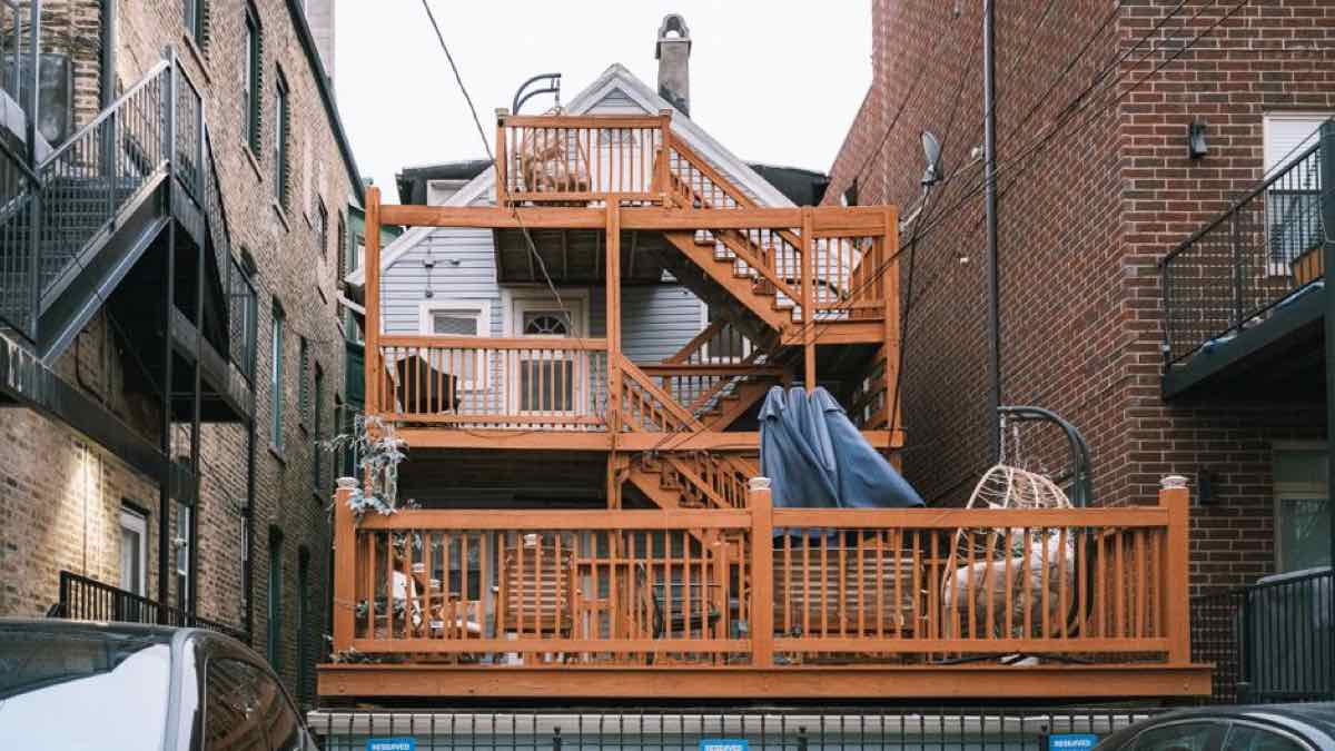 Multi-tier wooden back deck and staircase on an older New England-style home