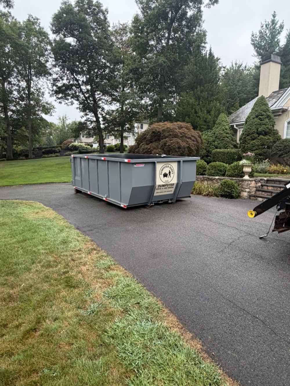 20-yard grey roll-off dumpster parked in a driveway