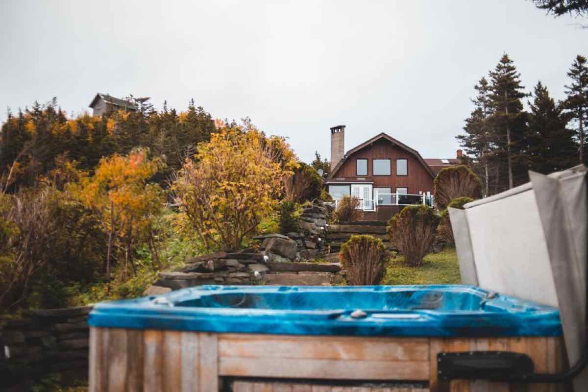 Old blue hot tub sitting unused in a New England backyard with fall foliage