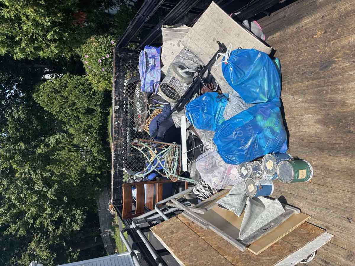 Trailer loaded with old paint cans, plywood, and household items