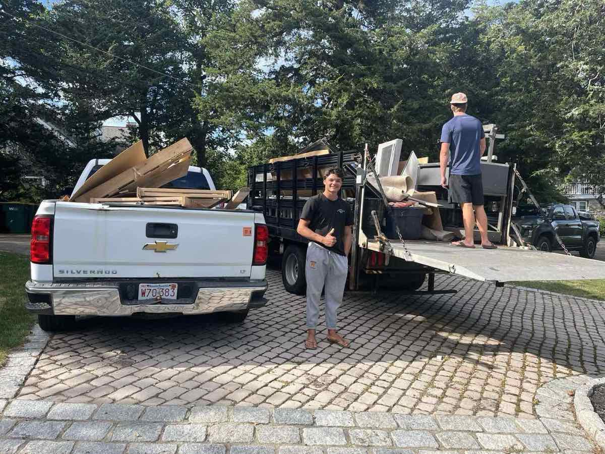 Dumpster Dudes crew loading furniture and debris onto a truck in a Hull, MA driveway