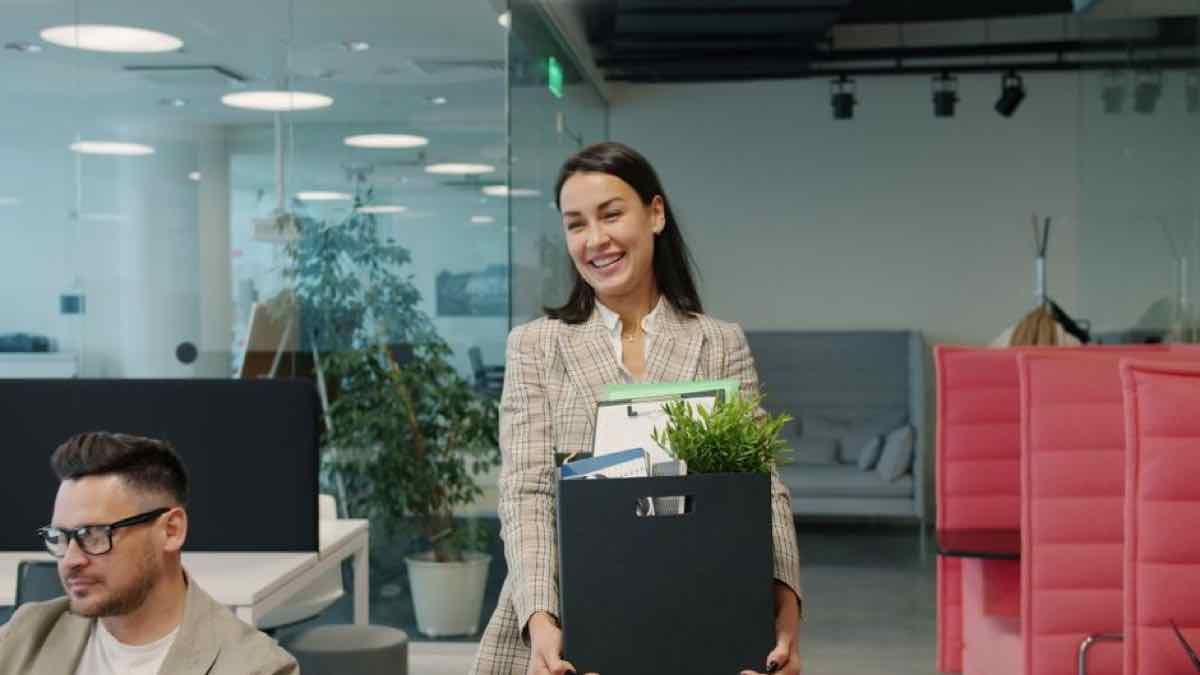 Employee carrying a box of desk items and a plant out of a modern office