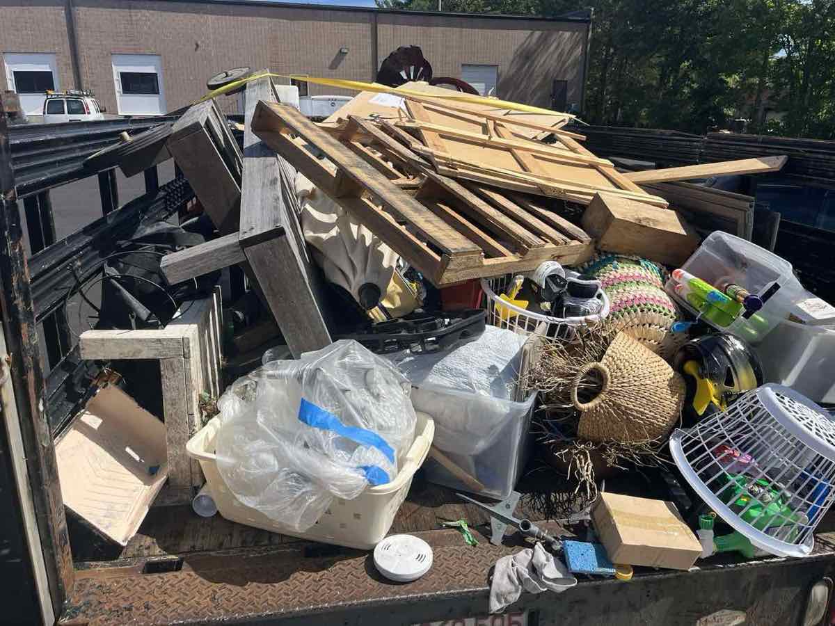 Mixed load of patio furniture, tools, and household items staged for sorting