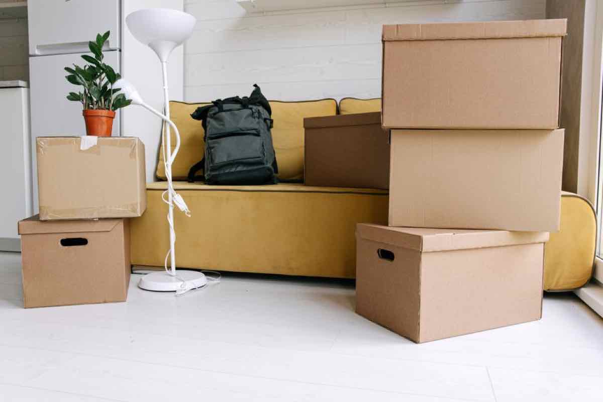 Stack of packed moving boxes next to a couch in a living room, ready for a whole-house cleanout